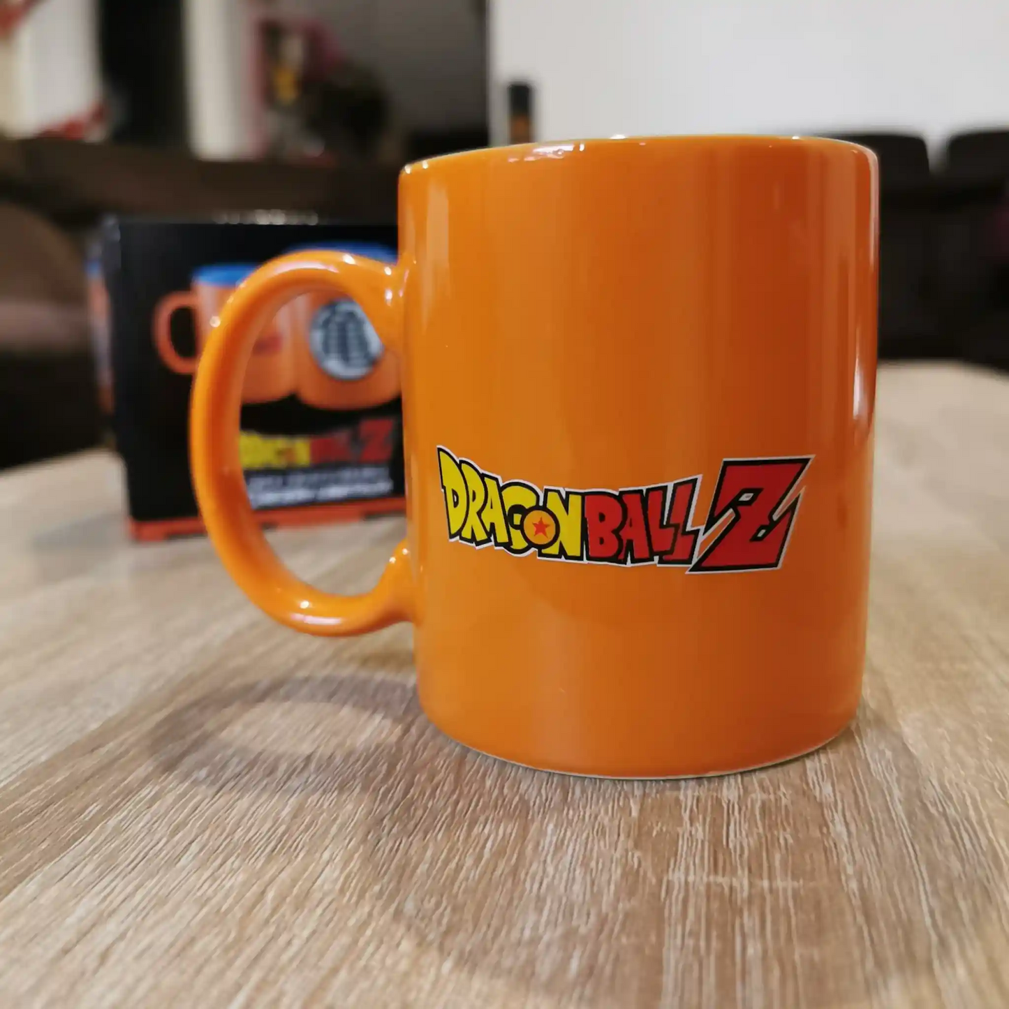 Taza de Dragon Ball Z con el logotipo clásico de la serie, sobre una mesa con fondo desenfocado.