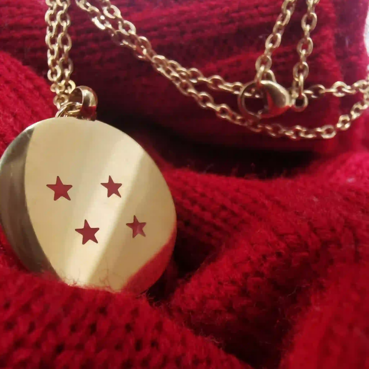Dije dorado con 4 estrellas rojas inspirado en Dragon Ball Z sobre tela tejida roja