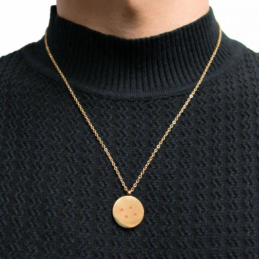 Persona usando collar dorado con dije de esfera de 4 estrellas de Dragon Ball Z sobre suéter negro