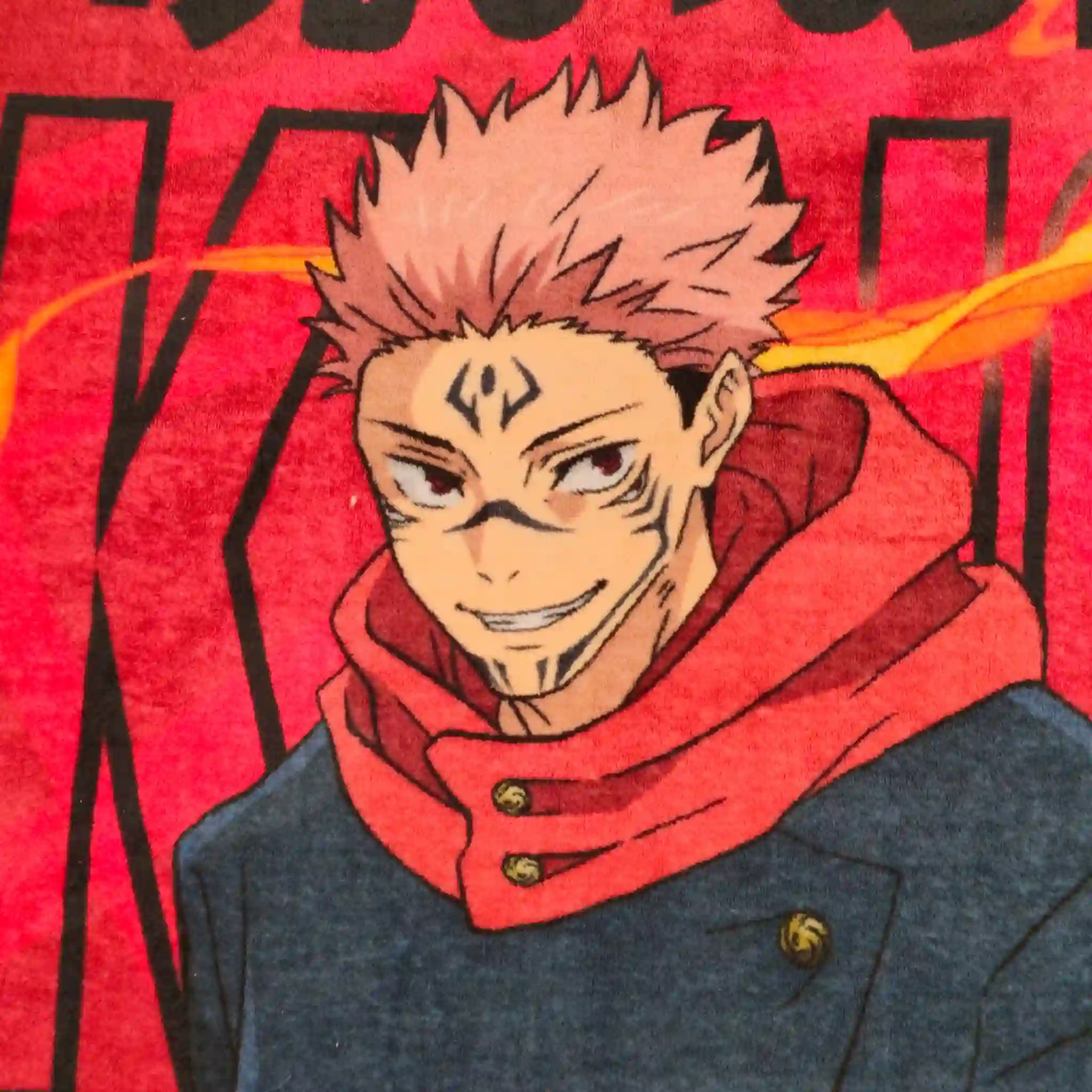 Primer plano del rostro de Sukuna en cobija de Jujutsu Kaisen con fondo rojo intenso