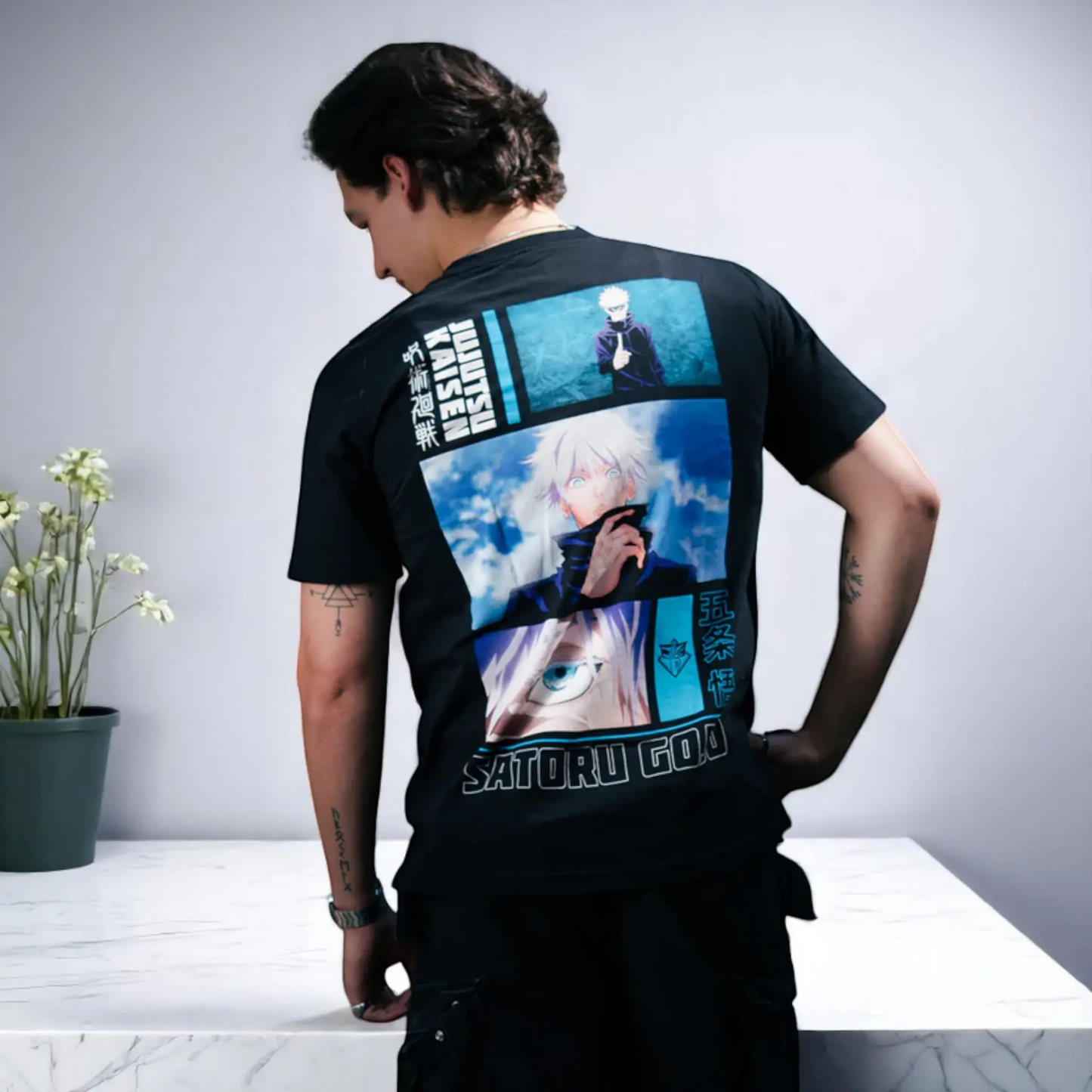 Modelo de espaldas usando playera oversize negra de Gojo Satoru de Jujutsu Kaisen, con diseño tipo collage en tonos azules.