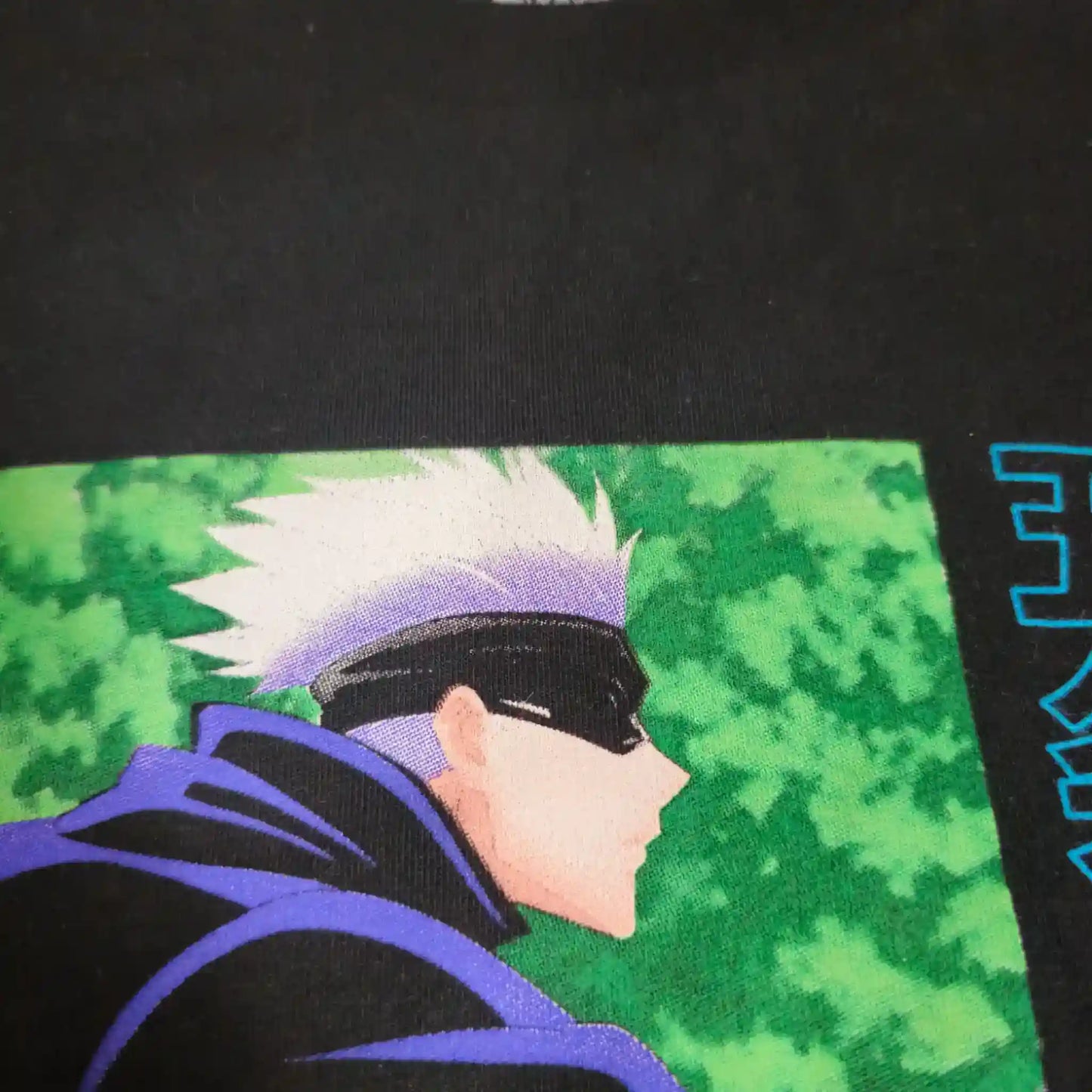 Detalle del estampado frontal de la playera oversize de Gojo Satoru, con fondo verde y letras japonesas en azul