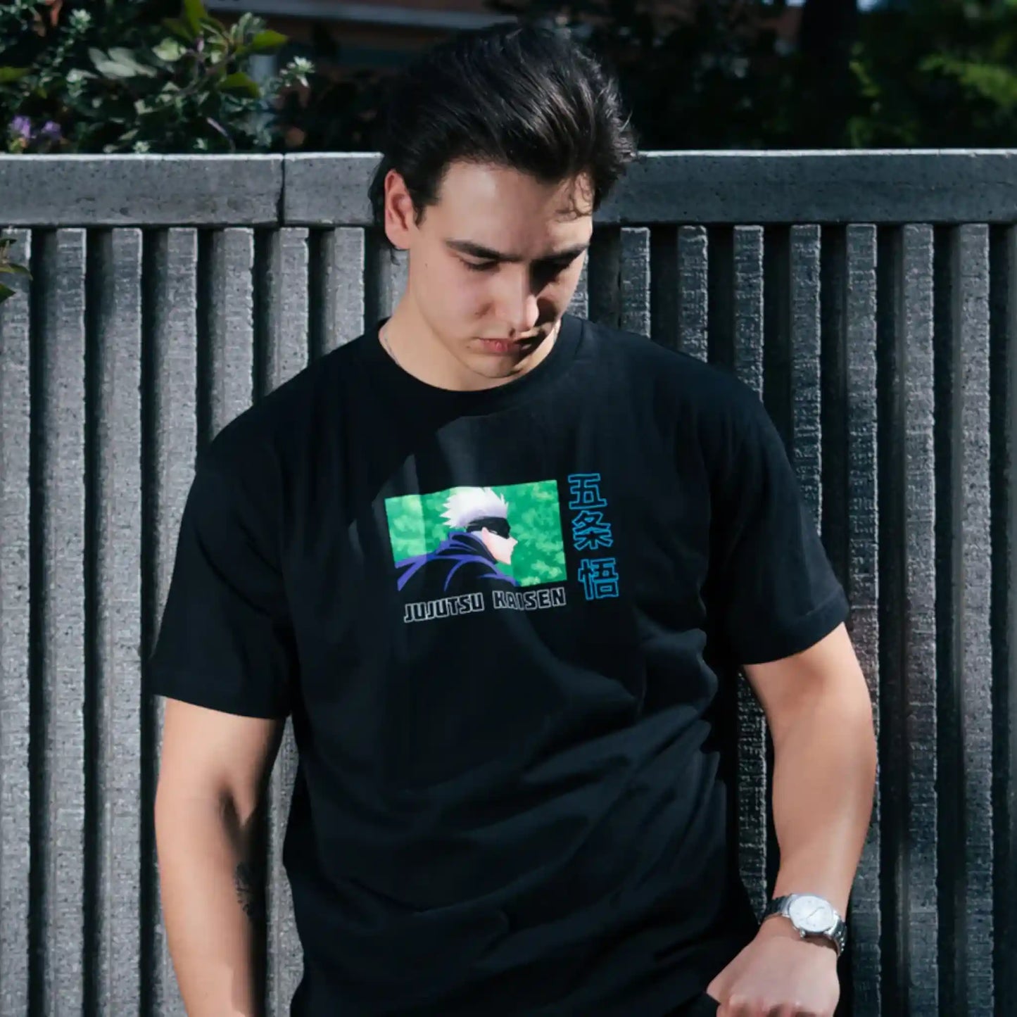 Modelo usando playera oversize negra de Gojo Satoru de Jujutsu Kaisen con diseño minimalista en el pecho, posando al aire libre